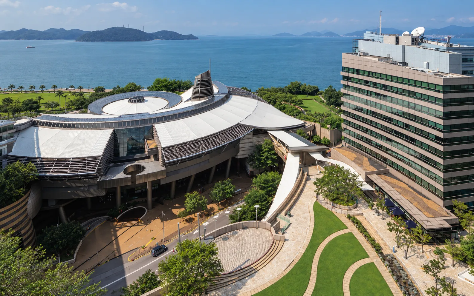 Aerial view of Cyberport in Hong Kong: curved white roofs, an office building and the sea