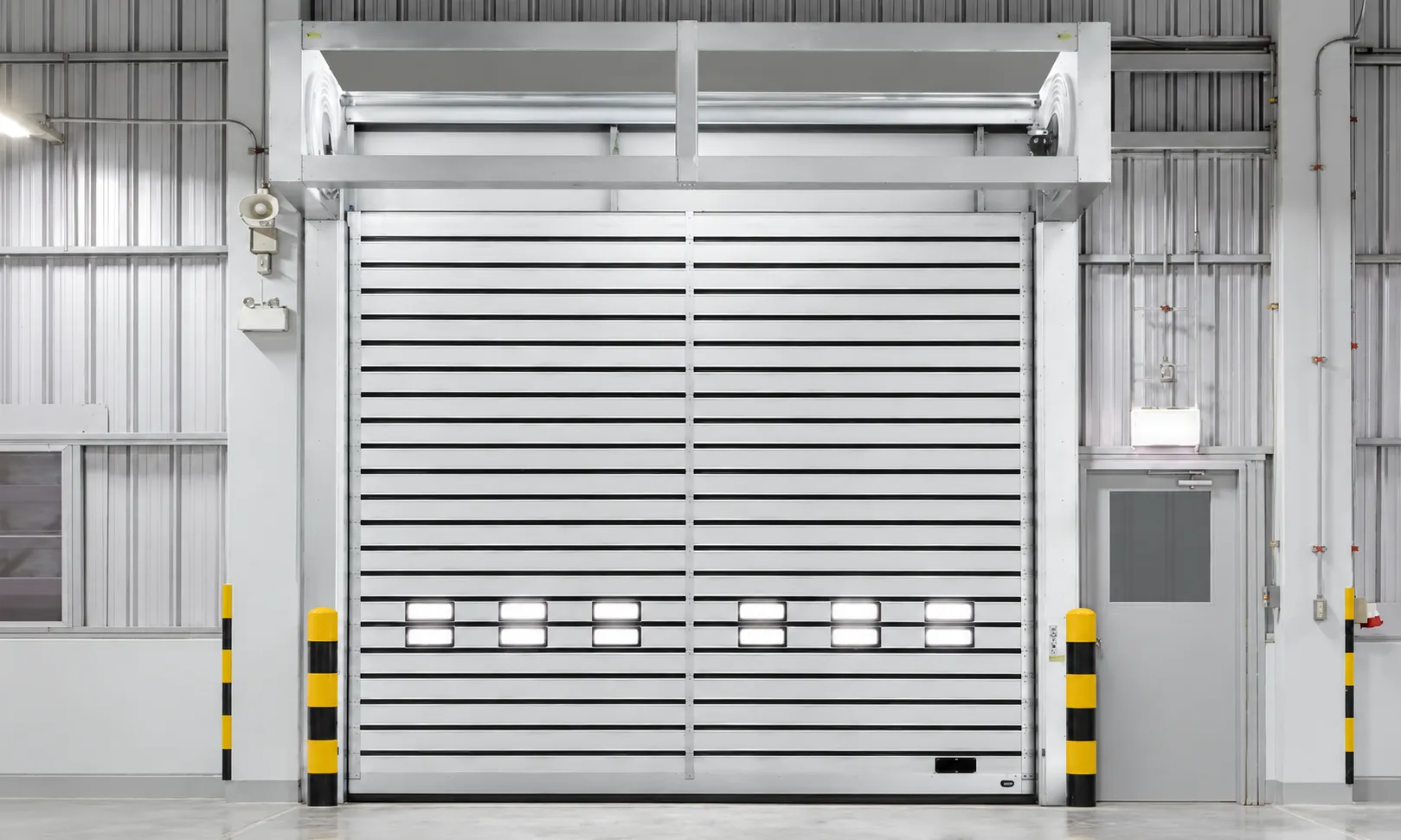 Aluminum high speed spiral door with a centre post and vision windows in a warehouse, bollards on both sides (rendering)