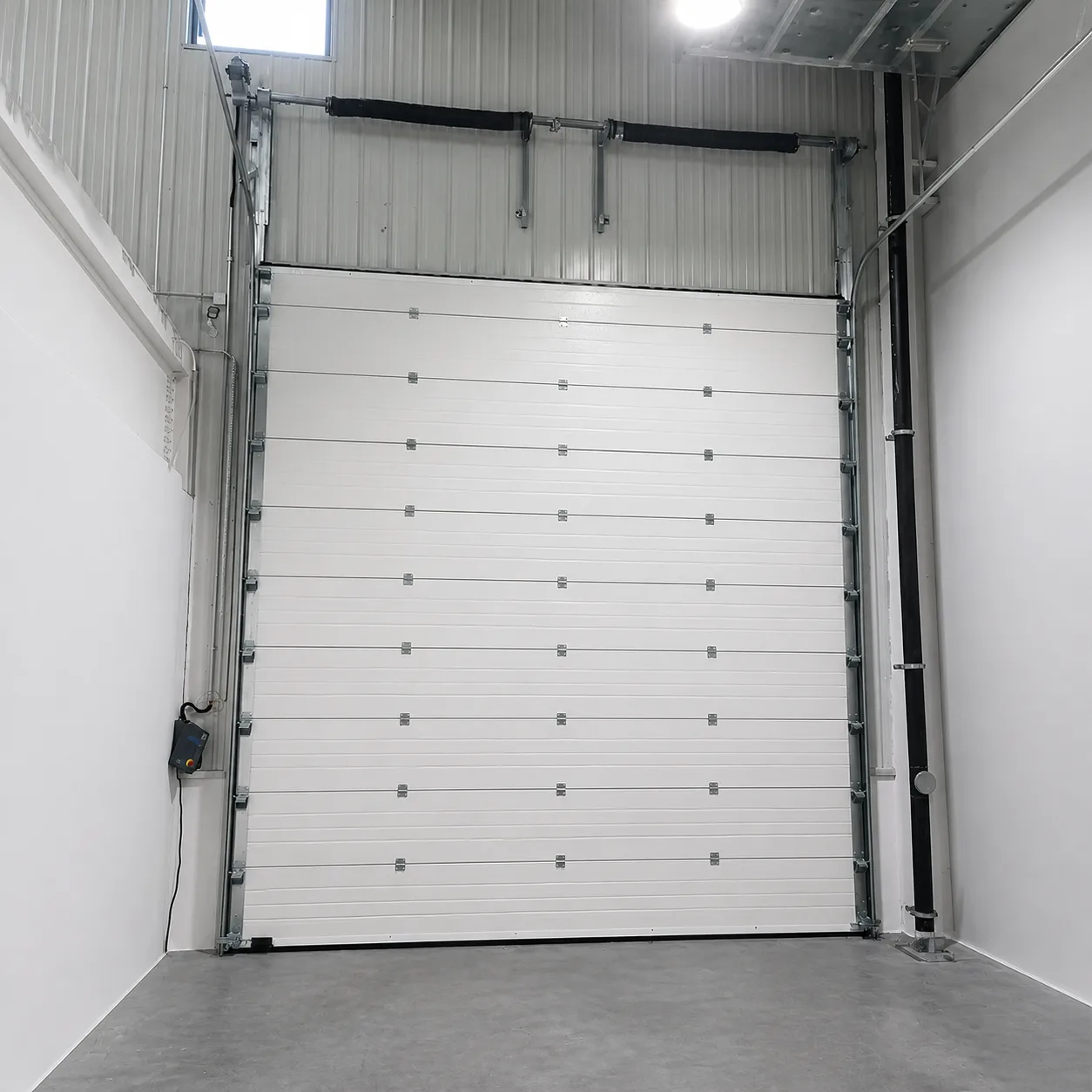 White insulated sectional door with torsion springs above the opening and a side-mounted operator, in a new steel-frame building