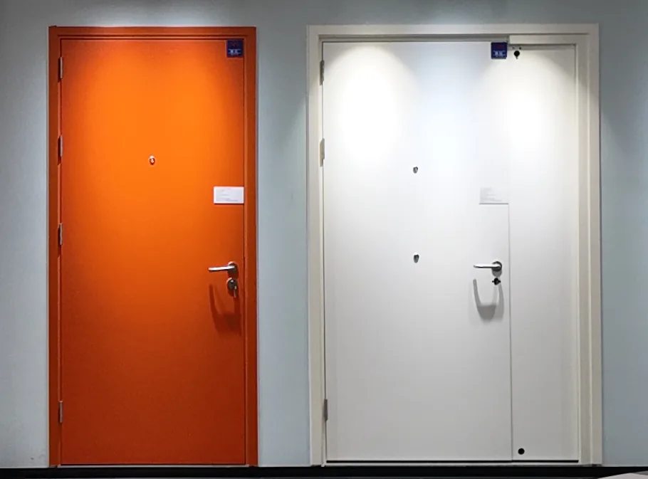 Orange steel single door and white steel leaf-and-a-half door side by side on a showroom wall