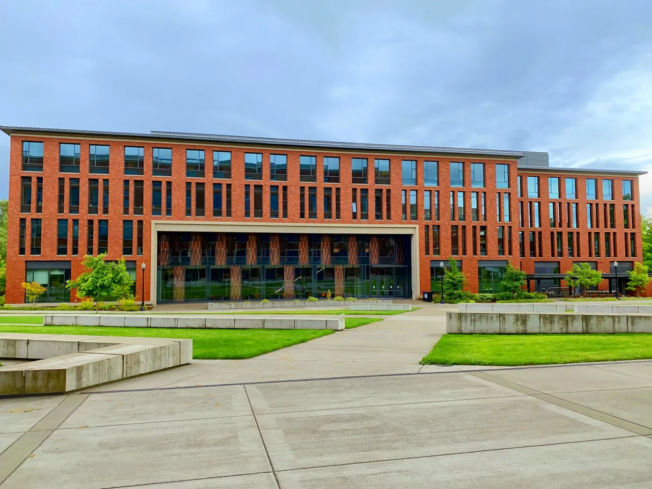 Red-brick university building with a glazed entrance and a lawn